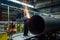 Worker cleans welded seam on steel pipe using grinding machine in metalwork workshop