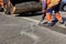 A worker clears a piece of asphalt with a pneumatic jackhammer in road construction