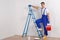 A worker climbs on a ladder with a bucket on a white background