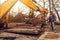 The worker clings the chain to the excavator bucket to raise the concrete slab