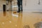 Worker, coating floor with self-leveling epoxy resin in industrial deposit