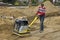 Worker compacting sand with vibrating plate tamper