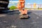 Worker compacts tarmac using vibration plate compactor