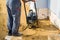 worker compresses sand in blind area around building with special working tool & x28;tamping machine or vibratory plate