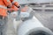 A worker at the construction site cutting concrete drainage pipe with a concrete saw..Builder covered in a hazardous dust cloud