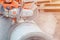 Worker at the construction site cutting a concrete drainage pipe with a petrol concrete saw. Builder covered in a hazardous dust