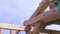 Worker at the construction site during the process of wooden house building on blue cloudy sky background. Clip. Men