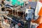 Worker is controlling tarmac road laying machine with remote handlebars, operating console