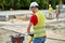 Worker in cotton gloves and a hardhat compacting the ground