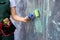 Worker in coverall painting wall with roller in green color close up