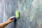 Worker in coverall painting wall with roller in green color close up