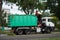 Worker with a crane on truck removing tree branches after cutting at the urban park in the street