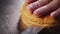 Worker cuts hamburger bun with sesame seeds on metal table