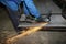 A worker cuts an iron mesh netting with an iron circle. Sparks fly