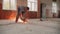 A worker cuts metal structures on the floor using a grinder.