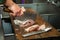 Worker cutting fish on a board at the restaurant kitchen