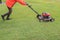 Worker cutting green grass field by engine lawn mover