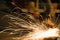 Worker cutting metal with grinder, sparks while grinding iron. Low key photography