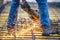 Worker cutting steel, sawing reinforced bars using angle grinder mitre saw