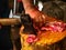 Worker cutting white pork meat on a wooden log full of blood