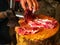 Worker cutting white pork meat on a wooden log full of blood