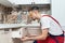 Worker dressed in workers` overall assembing furniture in kitchen