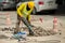 Worker drilling concrete driveway with jackhammer.