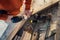 A worker drills a hole in wooden bar with drill