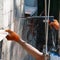 A worker drills the wall of multistory building with an electric drill.