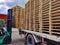 Worker driving forklift to loading and unloading wooden pallets from truck to warehouse cargo storage, shipment in logistics and