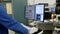 A worker at a factory stands in front of a computer monitor looking at an electrical circuit