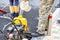 A worker fills the plastic tank of an old compact plate with water at a work site