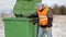 Worker with garbage bags near the container in winter