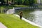 The worker of a garden cuts off a grass near the pond in Kalinigrad