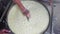 A worker in gloves mixing pieces of a soft cheese in the vat with a big iron plate at the factory