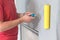 a worker glues wallpaper on the wall with a fireplace using a rubber roller.