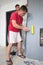 a worker glues wallpaper on the wall with a fireplace using a rubber roller.