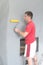 a worker glues wallpaper on the wall with a fireplace using a rubber roller.