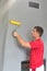 a worker glues wallpaper on the wall with a fireplace using a rubber roller.