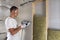 Worker in goggles with screwdriver working on insulation. Drywall on wall beams, insulating rock wool staff in wooden frame.