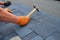Worker hands installing bitumen roof shingles using hammer in nails