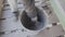 Worker hands are mixing wet concrete mass with paint brush in bucket