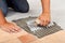 Worker hands spreading adhesive for ceramic floor tiles