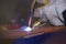 worker hands welding metal plates with semi-automatic welder at a workshop