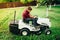 Worker, handyman trimming grass using lawn mower