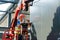 A worker in a hanging cradle attaches wall panels at the construction site of a medical aid and rescue center on a sunny summer