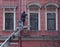 Worker hangs holiday garlands on the wall of a house, 176 Nevsky Prospekt, Saint Petersburg, Russia, December 2020