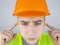 A worker in a hard hat and green vest puts on ear plugs. Industrial safety. Industrial noise protection. Compliance with the rules