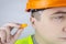 A worker in a hard hat and green vest puts on ear plugs. Industrial safety. Industrial noise protection. Compliance with the rules