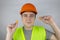 A worker in a hard hat and green vest puts on ear plugs. Industrial safety. Industrial noise protection. Compliance with the rules